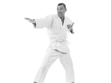 Man in white martial arts uniform performing a karate stance.