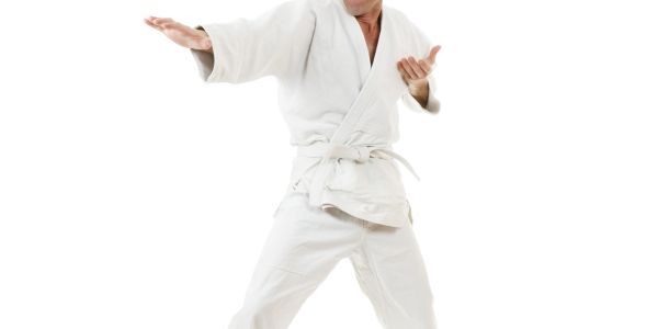 Person in a white martial arts gi performing a karate stance.