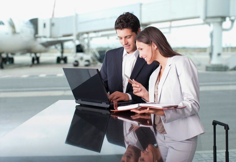 Business people using laptop together at airport