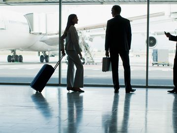 Business travelers talking in airport terminal near airplane.