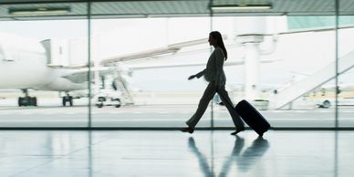 Businesswoman walking with luggage in an airport terminal.