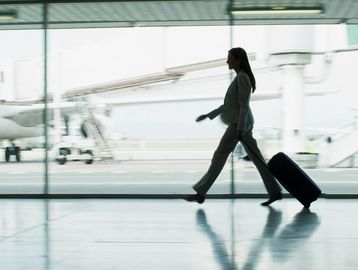 Businesswoman walking with luggage in an airport terminal.