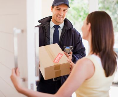 Delivery person handing package to a customer at their home.