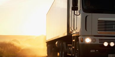 Truck driving at sunset on a rural road.