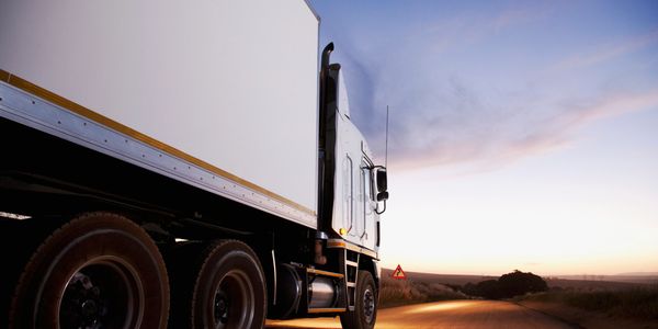 A large truck parked on a rural road during sunset.