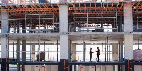 Two construction workers talking on a building site.