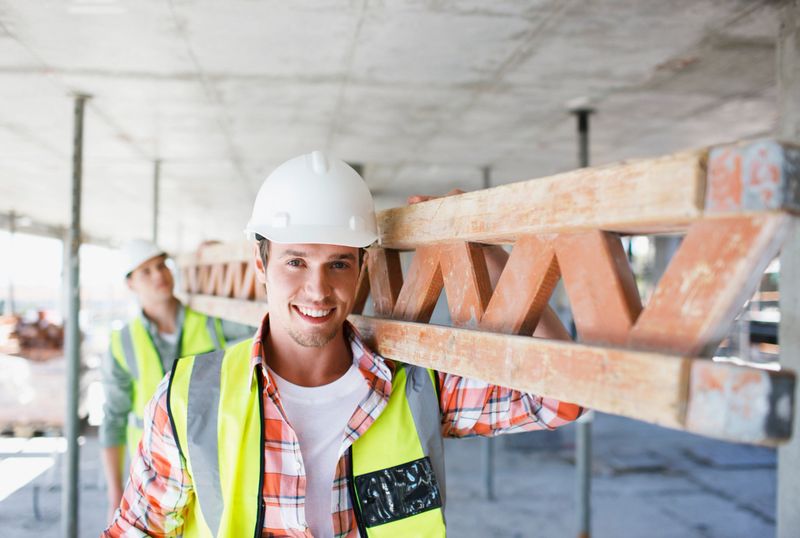 Construction worker carrying girder on construction site