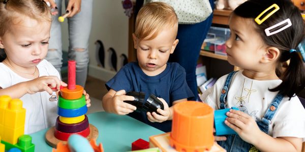Three toddlers playing with colorful educational toys at a daycare.