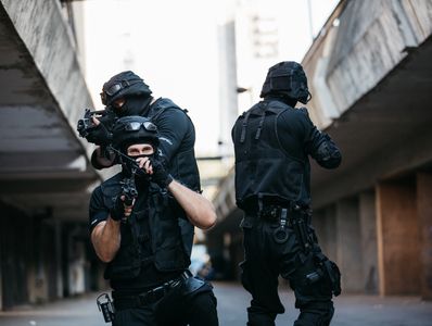 Three tactical police officers in black gear aiming their weapons in an urban setting.
