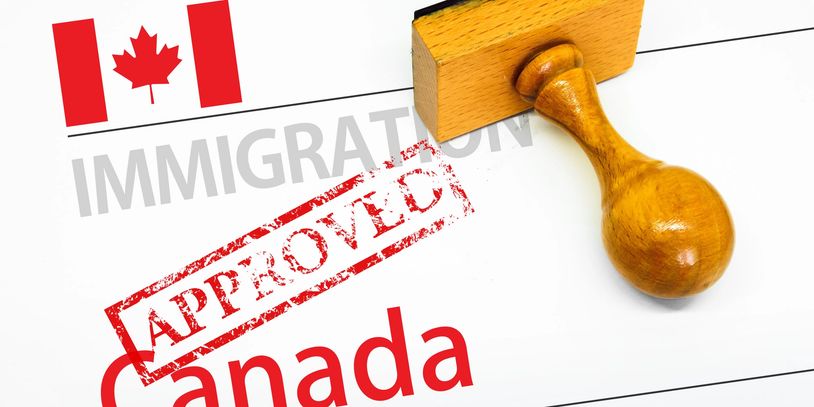 Wooden stamp marked "APPROVED" on Canadian immigration document.