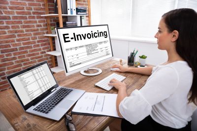 Woman working on e-invoicing with two computer screens.
