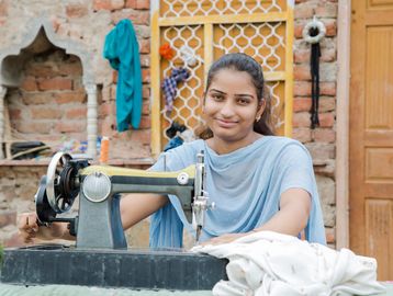 Young woman using a sewing machine outdoors.