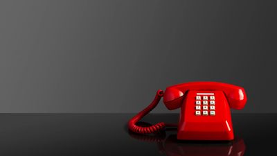 A classic red rotary phone against a dark background.