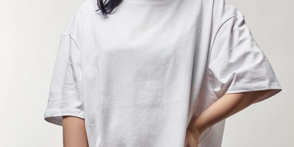 Person in a loose white t-shirt with one hand on hip.