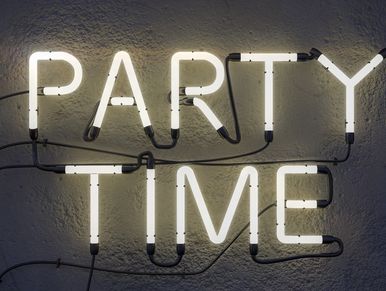 Neon sign glowing with the words 'PARTY TIME' on a textured wall.