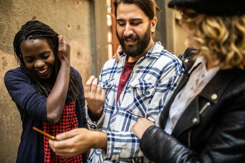Group Of Pretty Young Friends Walking in the City and Using Phone To Find Direction In Map App