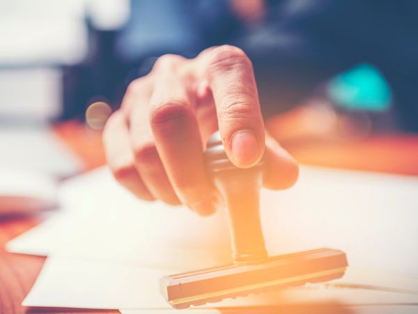 Hand pressing a rubber stamp on a document.