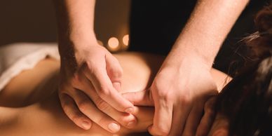 Hands giving a deep tissue massage on a person's back.