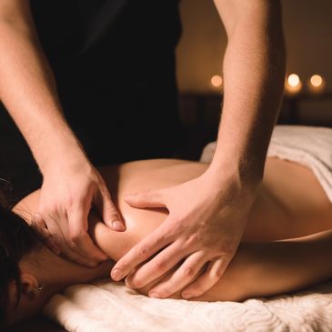 Person receiving a relaxing shoulder massage in a dimly lit room.