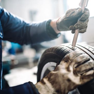 Mechanic measuring tire tread depth with a tool.
