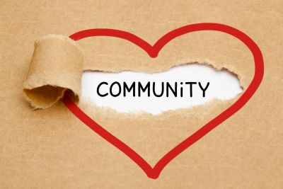 Torn paper reveals the word "Community" inside a red heart.