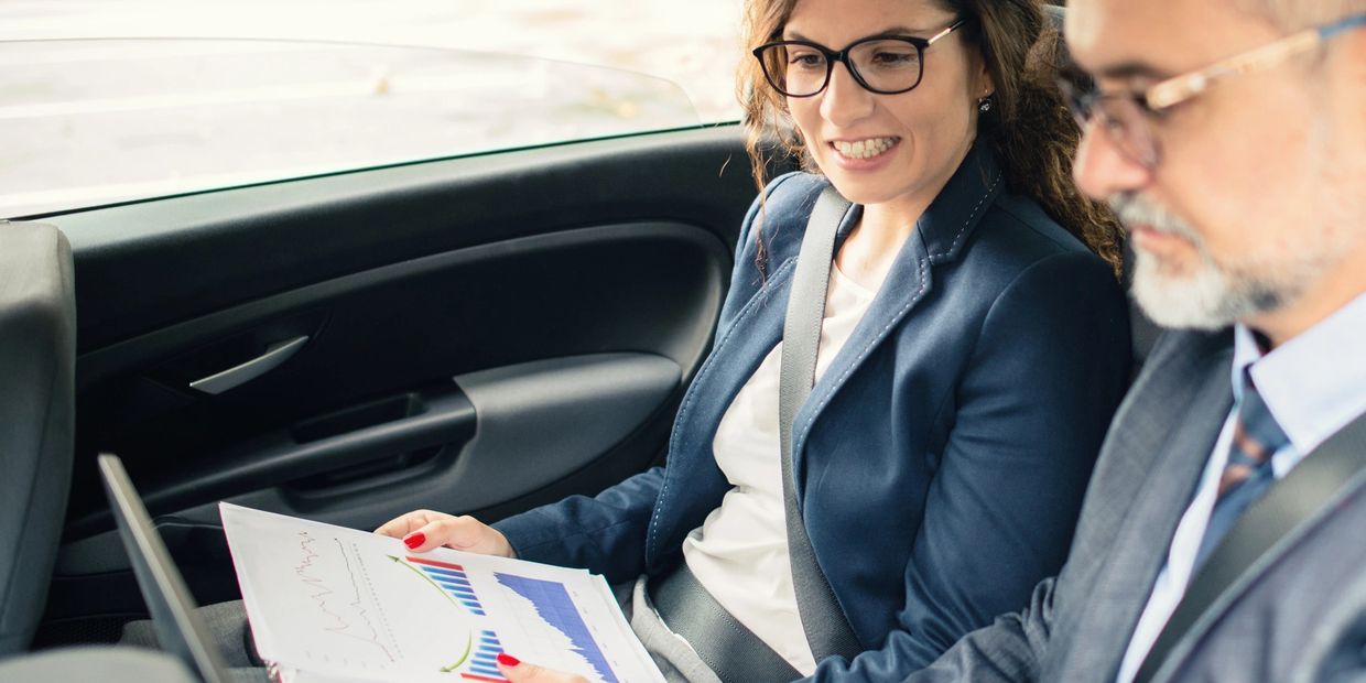 Two business professionals reviewing charts inside a car.