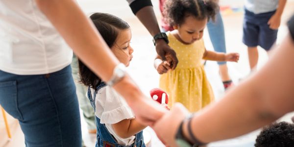 Children holding hands in a circle with adults.