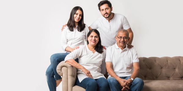Family portrait with four people smiling on a couch.
