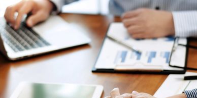 Two people working with charts and a laptop in a meeting.