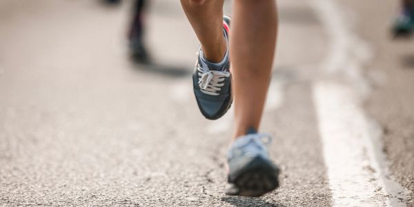 Close-up of runners' feet during a marathon on a sunny day.