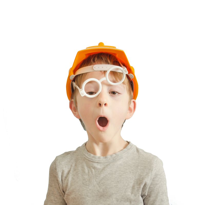 Boy in the helmet of the builder and glasses. Surprised face. Isolate