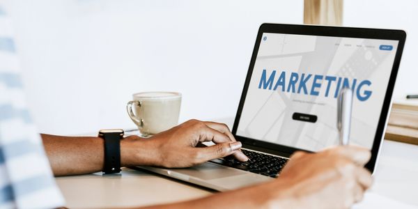 Person working on marketing strategy on a laptop with coffee nearby.