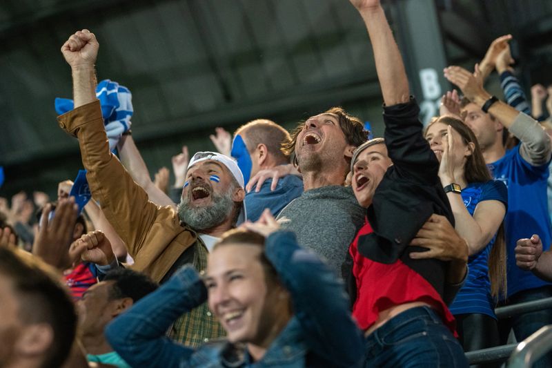 Group of friends on stadium bleachers embracing and celebrating the success of their team.