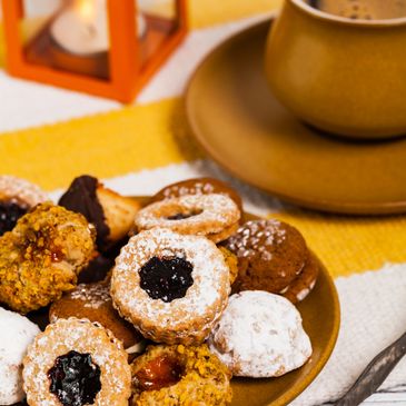 A plate of assorted cookies with a cup of coffee on a yellow-striped cloth.