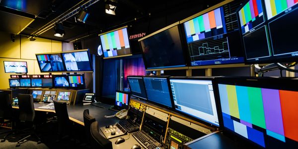 High-tech broadcast control room filled with multiple monitors and equipment.