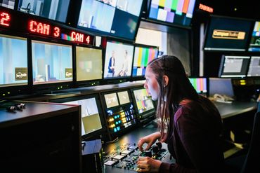 A woman operates video controls in a broadcast control room.