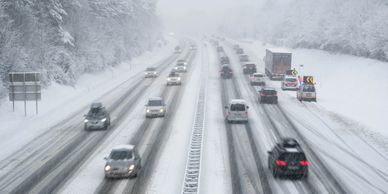 Snow-covered highway with cars driving cautiously in winter conditions.