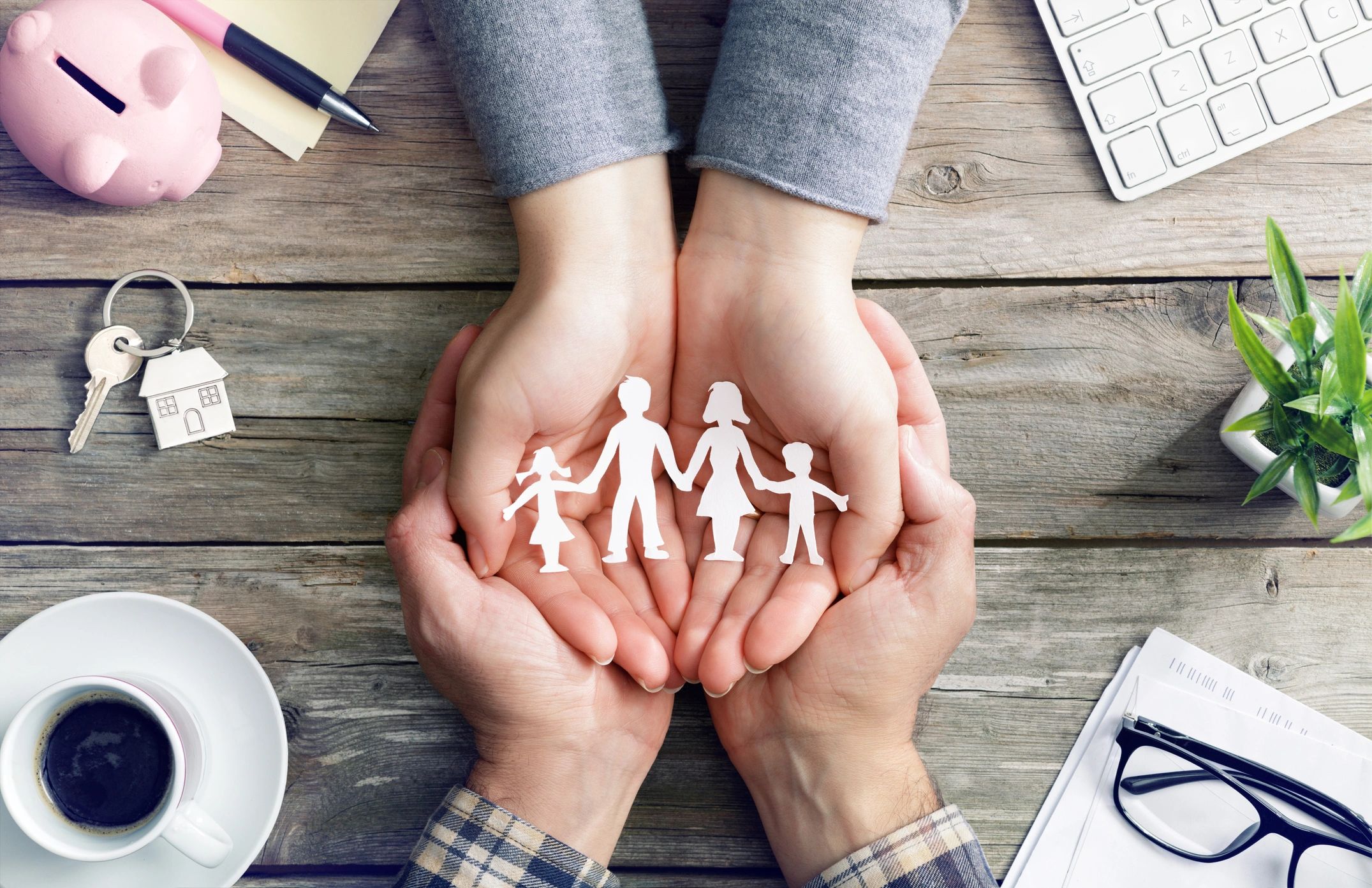 Hands holding paper family cutout symbolizing protection.