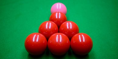 Six red snooker balls in a triangle formation.  Pink snooker ball above the six red snooker balls.