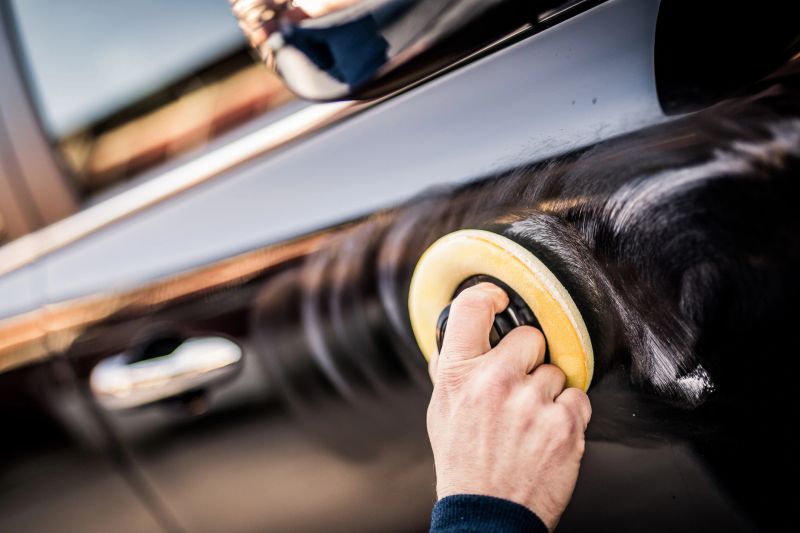 Close-up of mature man applying foam with pad on car.