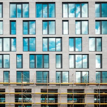 Modern building facade with reflective windows and scaffolding below.