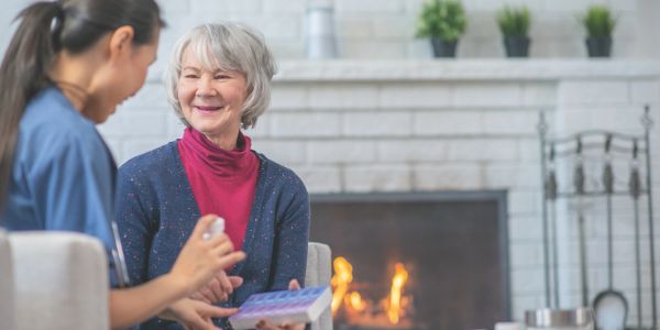 Senior woman smiling with a healthcare worker in a cozy home setting.