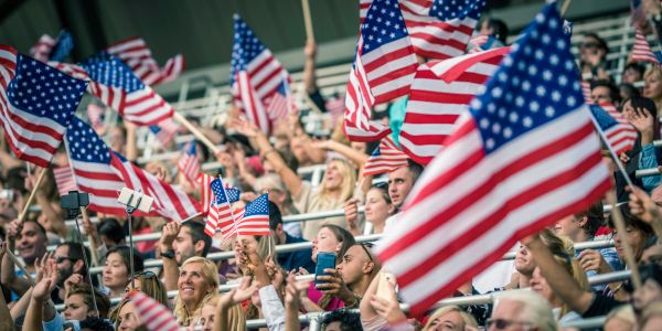 Crowd waving American flags at an event.