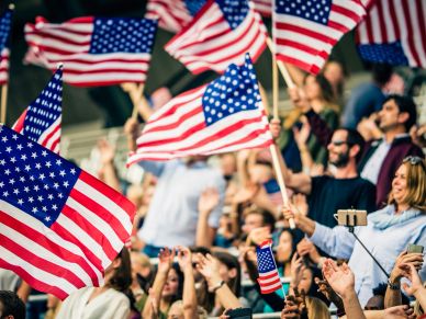Crowd waving American flags at an event.