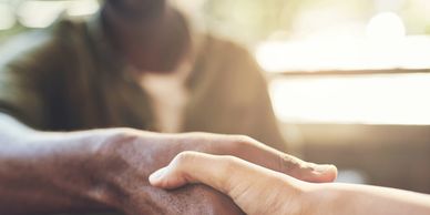 Two people clasping hands in a warm gesture of support.