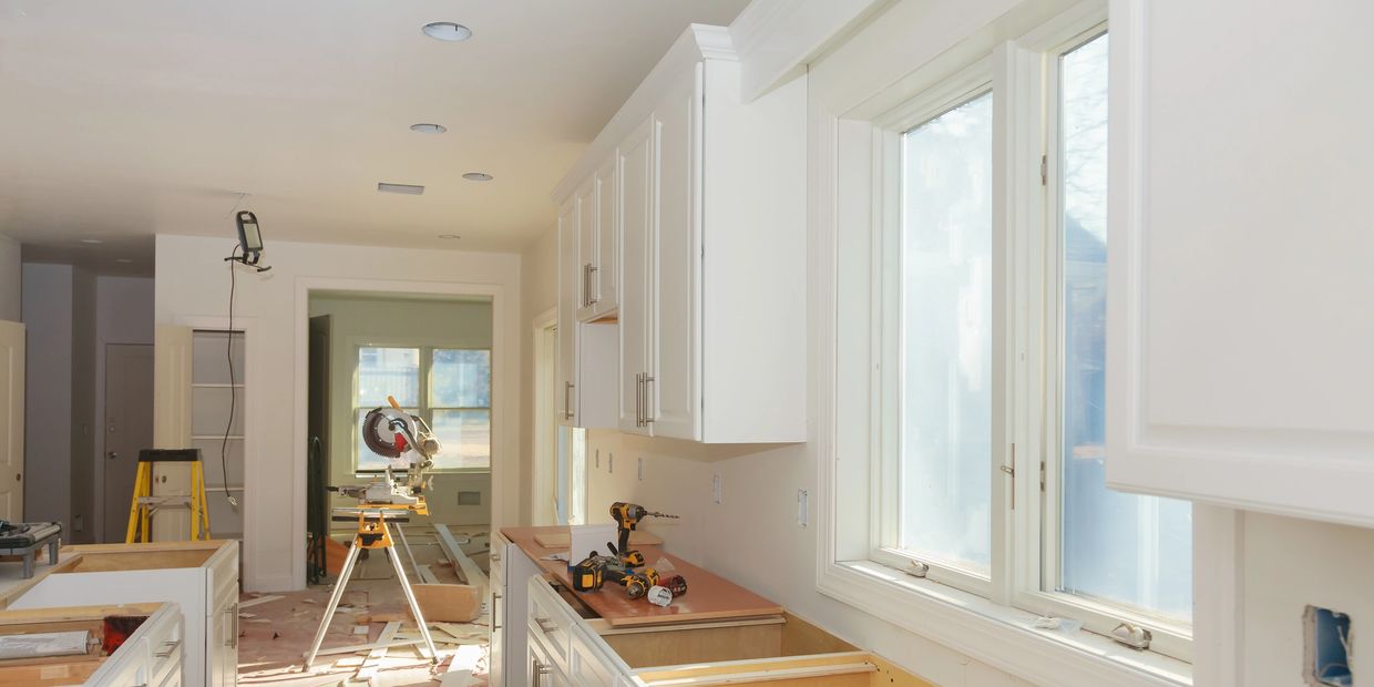 Kitchen under renovation with tools and new cabinetry installed.