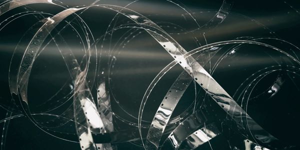 Coiled transparent film strips with a dark background.