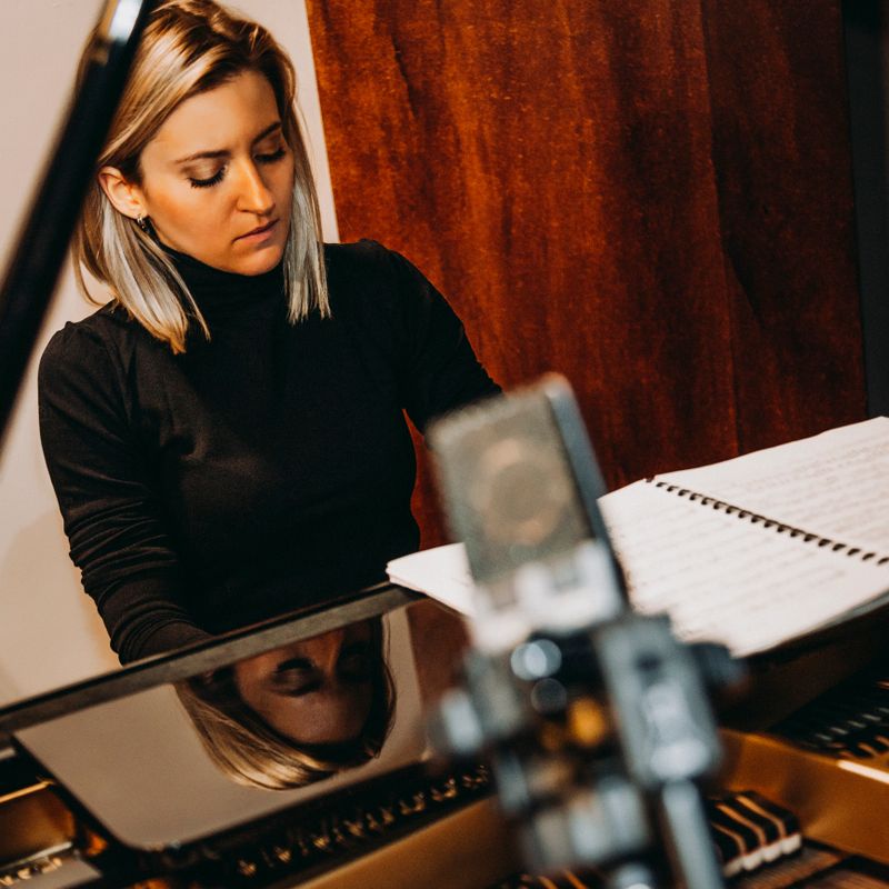 Female composer playing piano at sound recording studio.