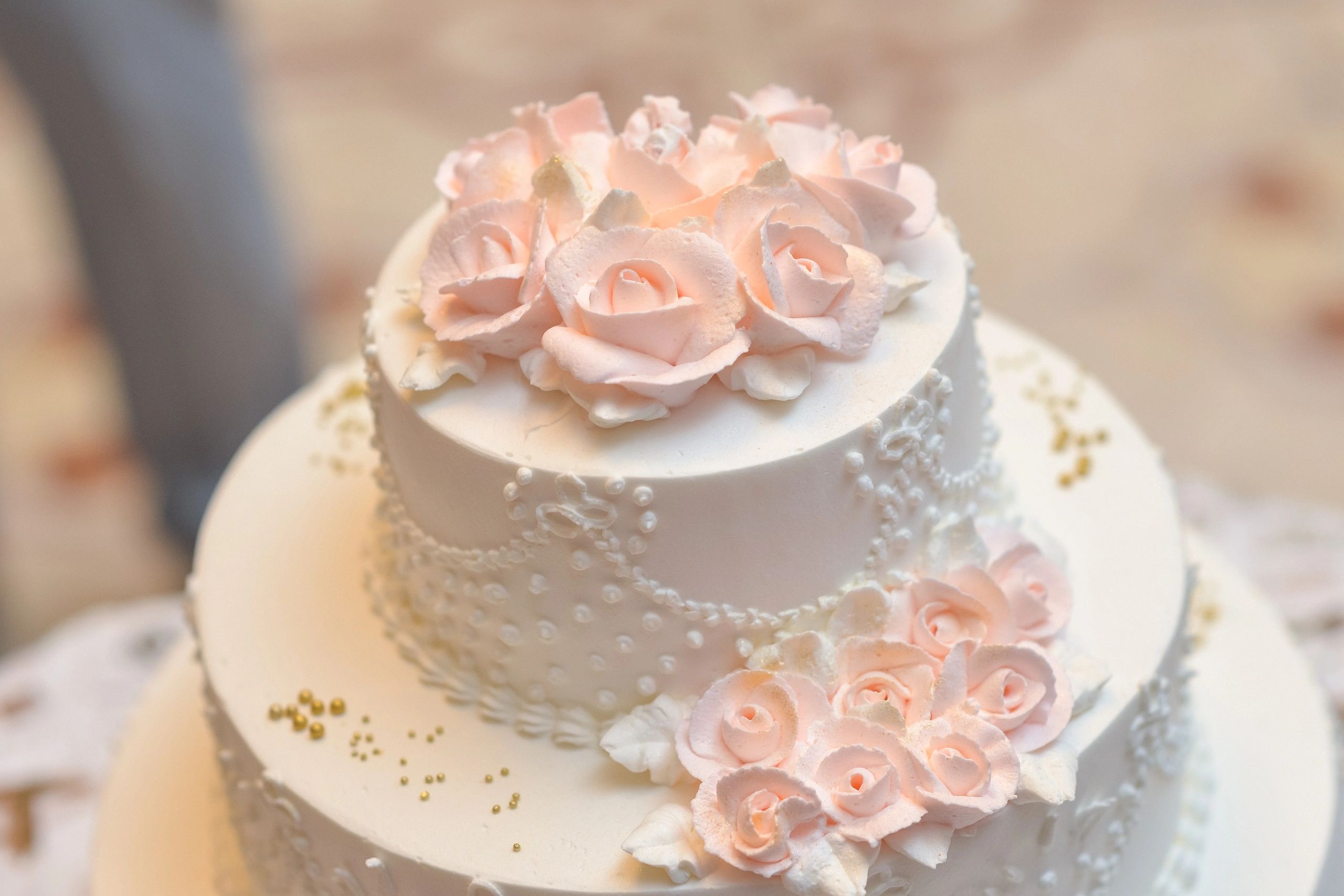 Elegant white cake adorned with delicate pink rose decorations.