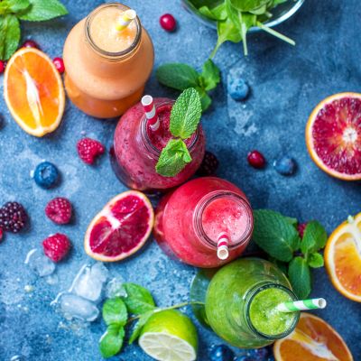 Colorful fruit smoothies with fresh fruits and mint leaves.